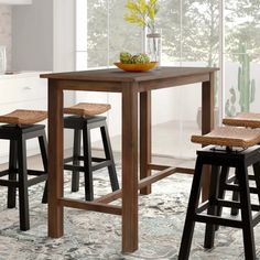 a kitchen table with two stools and a bowl of fruit on the counter top