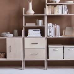 a book shelf with several books and baskets on it, along with two vases