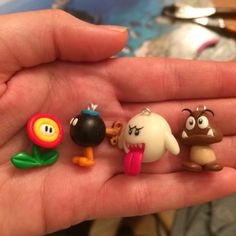 a hand holding five different toy figures in it's palm, one is small and the other is larger