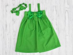 This green light and breezy halter sundress will keep your little one cool in the summer and is roomy and comfortable to allows plenty of room for movement and growth. The tie dye fabric extra large bow on the bodice coordinates with the circled dots on the dress and headband. This dress features a split skirt in the back with snap closures. Take this outfit from summer into fall by layering with a long-sleeve shirt and pants or tights.   Ruffled edges and bow tie make this headband extra adorab Beach Cotton Dress With Bow Tie Back, Spring Playtime Dress With Bow, Beach Cotton Dress With Bow, Summer Cotton Dress With Bow Straps, Summer Cotton Dress With Bow Tie Back, Green Cotton Sundress, Green Sleeveless Dresses With Bow, Sleeveless Green Dress With Bow, Playful Green Sundress For Vacation