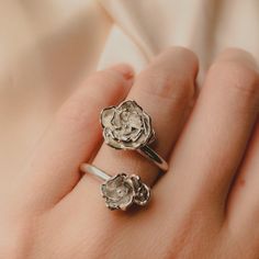 two silver rings sitting on top of someone's hand with their fingers in the air