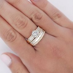 a woman's hand with two wedding rings on her left and the other hand holding an engagement ring