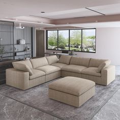 a living room with a sectional couch and ottoman in front of a large window that looks out onto the outdoors