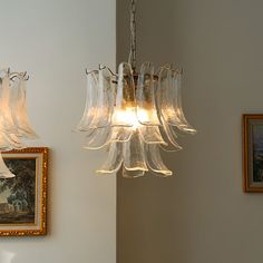 two chandeliers hanging from the ceiling in a room with pictures on the wall