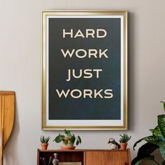 a framed poster that says hard work just works on the wall above a bookcase