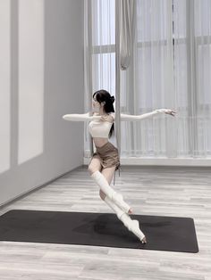 a woman is doing yoga on a mat in the middle of a room with windows