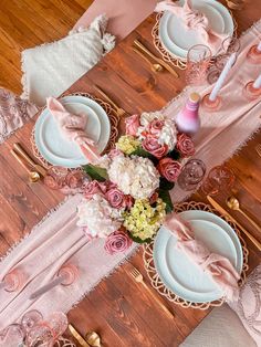 the table is set with pink and white plates, napkins, and flower centerpieces