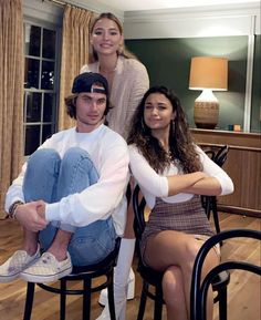 three people sitting on chairs in a living room