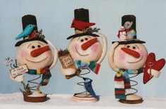 three snowmen with hats and scarfs are standing next to each other