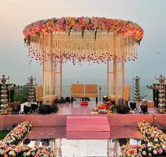 an outdoor wedding setup with flowers on the stage and chairs set up in front of it