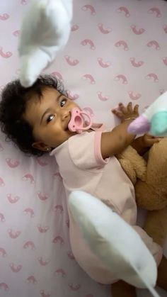 a baby laying on top of a bed next to a stuffed animal