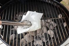 a person is grilling some food on the grill with tongs and paper towels