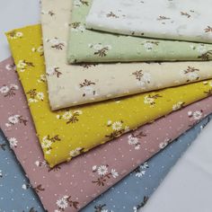 four different colored fabrics are stacked on top of each other, with small white flowers in the center