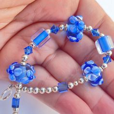 a hand holding a blue beaded bracelet