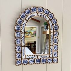 a blue and white mirror mounted to the side of a wall next to a table