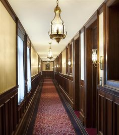 a long hallway with wood paneling and chandelier