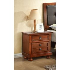 a wooden night stand with two drawers and a lamp on top of the table next to it