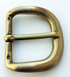 a gold metal buckle on a white wall