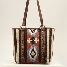 This Ariat wool blanket tote by M&F Western Products is brown with orange, blue and ivory in a southwestern pattern. Genuine leather on back, on handles and edge tooling. Zip closure on top of back to keep your items safe. Details Ariat Wool Blanket Tote Brown Measures: 15 x 13 x 4-1/2 Southwestern Pattern Genuine Leather Inside 2 Small Pockets, 1 Large Zip Pocket Zip Closure Brown Southwestern Style Shoulder Bag For Everyday Use, Southwestern Brown Rectangular Shoulder Bag, Southwestern Style Brown Rectangular Shoulder Bag, Brown Southwestern Rectangular Shoulder Bag, Southwestern Patterns, Brown Tote, M F, Wool Blanket, Tote Handbags