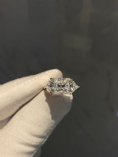 a person wearing a white glove holding an engagement ring with a diamond in the middle