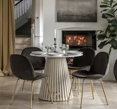 a dining room table with four chairs around it and a fireplace in the back ground