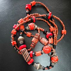 What a glorious blend of reds and browns - 22 inches of vintage beads from around the world.  I've included vintage Chinese cinnabar, contemporary red coral disks, a sterling capped red jasper bead and some other sterling beads. The primary beads used for the 'chain' are small rust colored glass beads from an old India NAGA necklace, interspersed with some rarer red green heart beads, black white heart beads and more recent faceted black glass beads.  For accents and contrast I added some vintage African trade beads - some brilliant red orange interlocking 'snake beads', a brown and black 'tic tac toe' bead and an unusual black African twirled stripe glass bead which I have been unable to identify but is most unique and shows signs of great age.  As you can see it's an unusual assemblage w