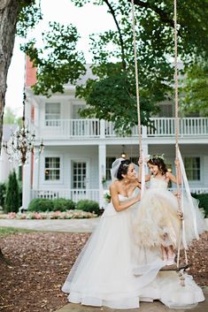 two brides on a swing in front of a house