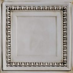 a white square with silver ornaments on the top and bottom, in an ornate frame