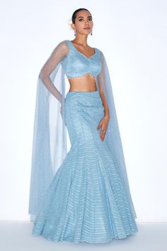 Blue mermaid style lehenga embellished with sequin scallop patterns. Comes with padded blouse with cape sleeves. 
Components: 2
Pattern: Embroidered
Type Of Work: Sequin
Neckline: V-neck
Sleeve Type: Cape sleeves
Fabric: Organza, net, Lining: Satin
Color: Blue
Other Details: 
Attached lining
Model Height: 6ft wearing size XS
Length: Lehenga: 45 inches
Closure: Lehenga and Blouse: Side zip
Occasion: Sangeet,Cocktail - Aza Fashions Blue Party Sets With Cape Sleeves, Glamorous Lehenga With Sequins And Cape Sleeves, Party Sharara With Cape Sleeves And Unstitched Blouse, Party Sharara With Cape Sleeves, Party Blue Choli With Cape Sleeves, Blue Lehenga With Cape Sleeves And Dupatta, Fitted Gown With Zari Work And Cape Sleeves, Party Wear Lehenga With Cape Sleeves And Dupatta, Fitted Lehenga With Cape Sleeves For Evening