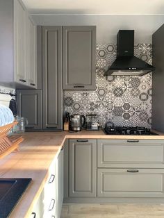 a kitchen with grey cabinets and wooden counter tops in front of a stove top oven