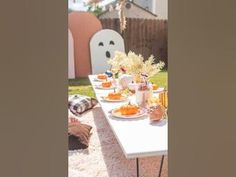 an outdoor table set up with pumpkins and other decorations