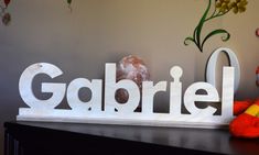 a wooden sign that says gabril on it next to a teddy bear and doughnut