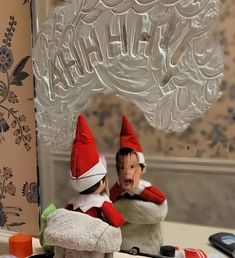 two elf figurines sitting on top of a bathroom counter next to a mirror