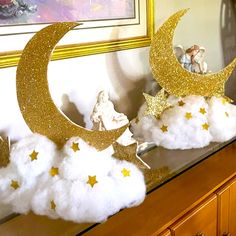 there are clouds and gold stars on top of the moon in front of an angel figurine