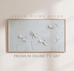 the frame is hanging on the wall with flowers painted on it in white and black