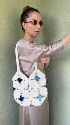 a woman wearing sunglasses is holding a white handbag with blue stars on the side