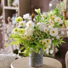 a vase filled with white flowers sitting on top of a wooden table next to a chair