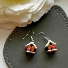 a pair of earrings with a gingerbread house on it