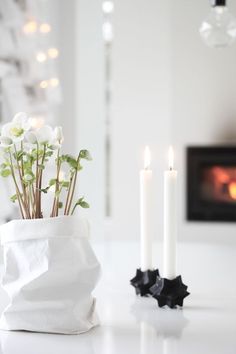 white flowers in a vase next to two candles