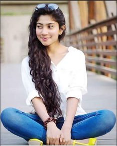 a young woman sitting on the ground with her legs crossed and holding onto a pair of yellow shoes