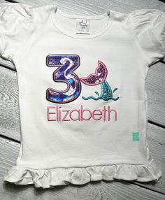 This is a custom embroidery Mermaid Tail  Birthday Theme Shirt! Mermaid  Birthday Shirt|  Sparkle Under the Sea Shirt| Custom Sea Animals  Birthday Shirt| Mermaid Tail  Birthday Shirt| Girls Glitter Shells Top The shirts are personalized with ages 1 to 9. *Want to change the color scheme? No problem! Just message me or leave your requests at checkout. Please note that all my embroidered items have a soft backing cover to protect your little one skin from any irritation. The onesies and shirts I use are boutique quality!! They are 100% cotton and run true to size. The shirts have puffy sleeves and are girls fitted style. I used glitter materials, the birthday shirt can be customized in terms of colors ,so you can always message me and we can discuss! I am NOT RESPONSIBLE for costumer error Customizable Fitted T-shirt For Birthdays, Fun Fitted T-shirt For Birthday, Customizable Fitted T-shirt For Birthday, Customizable Fitted T-shirt For First Birthday, Blue Fitted Top For Birthday, Fitted Blue Top For Birthday, Long Sleeve Summer Shirt For Birthday, White Fitted T-shirt For Birthday, Fitted Short Sleeve Tops For Birthday