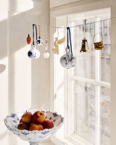 a bowl filled with fruit on top of a table next to a window sill