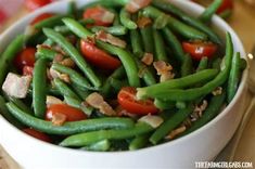 a white bowl filled with green beans and tomatoes