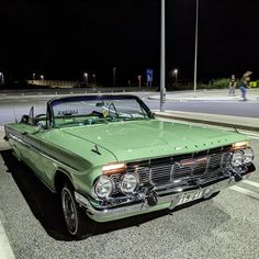 an old green car is parked on the street