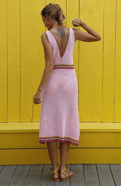 a woman standing in front of a yellow wall with her back turned to the camera