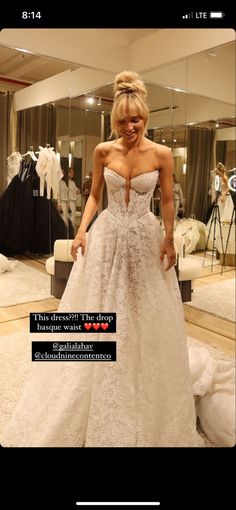 a woman in a wedding dress is looking at her cell phone while standing in front of a mirror