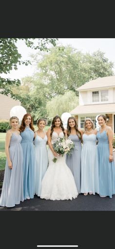 a group of women standing next to each other in front of a house