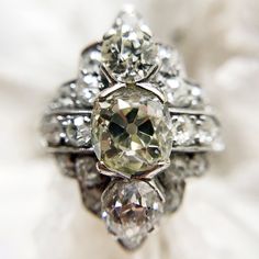 Platinum vintage art deco ring from the 1920's with 3.46 ctw. 1.65ct Center old mine cut diamond. SI-1 clarity grade. O-P Color grade. .81 ct matching round brilliant cut diamonds above and below center diamond. 22 round, full cut diamonds surrounding the center with 1ctw. Shield height is 2cm. Platinum band is 1.5mm at the back. GIA certified Appraisal on hand. Size 5.75 in stock Shipping and Delivery: IN STOCK items will ship within 2 business days Sizes not In Stock will be Resized Resize Fee Art Deco Diamond Ring, Deco Diamond Ring, Titanic Jewelry, Vintage Art Deco Rings, Art Deco Lady, Vintage Jewellery Rings, Old Mine Cut Diamond, Art Deco Diamond Rings, Antique Diamond Rings