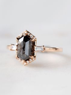 an engagement ring with a black diamond and two white diamonds on the side, set in yellow gold