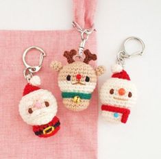 two crocheted christmas ornaments are hanging on a pink cloth